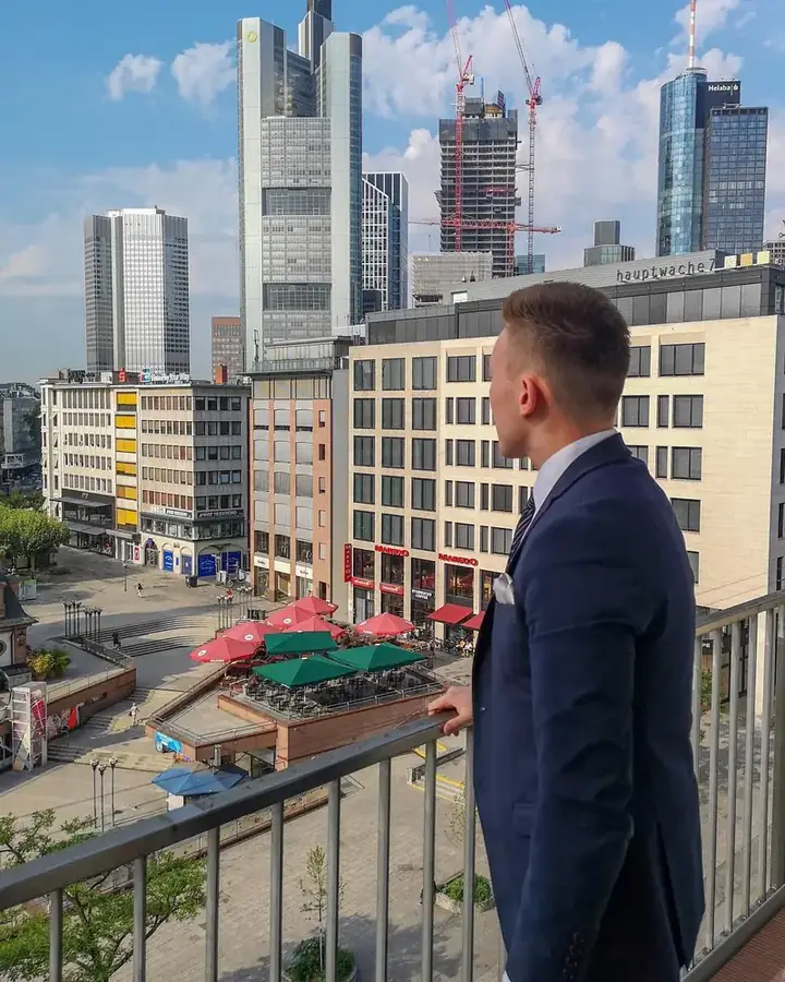 Arthur Hof in a suit on a balcony in front of a skyline